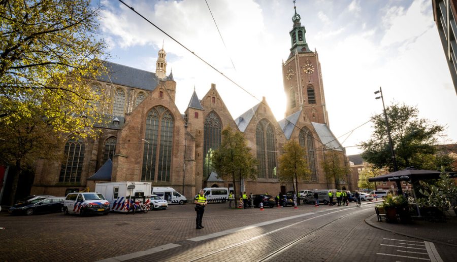 Kerk met zonlicht erachter. Voor de kerk staan veiligheidsmensen die een controle uitvoeren.
