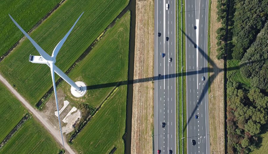 Bovenaanzicht van windmolen en snelweg tussen de polders.