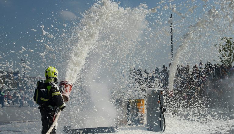 Een brandweerman blust een vuur met een brandweerslang.